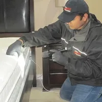 Bed bug inspection technician checking a mattress and bed frame for signs of infestation in Myrtle Beach, SC